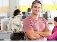 Smiling-man-with-arms-crossed-at-a-busy-creative-office.jpg